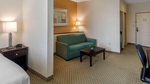 A hotel room with a bed, a green sofa, a small table with a plant, a lamp, and a chair. - Fairfield Inn & Suites Hillsboro (Hillsboro)