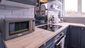 Une cuisine moderne avec des meubles gris, un four à micro-ondes encastré et une cuisinière.