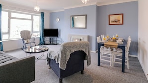Un salon comprenant un canapé, un fauteuil, un téléviseur et une table à manger avec des chaises.