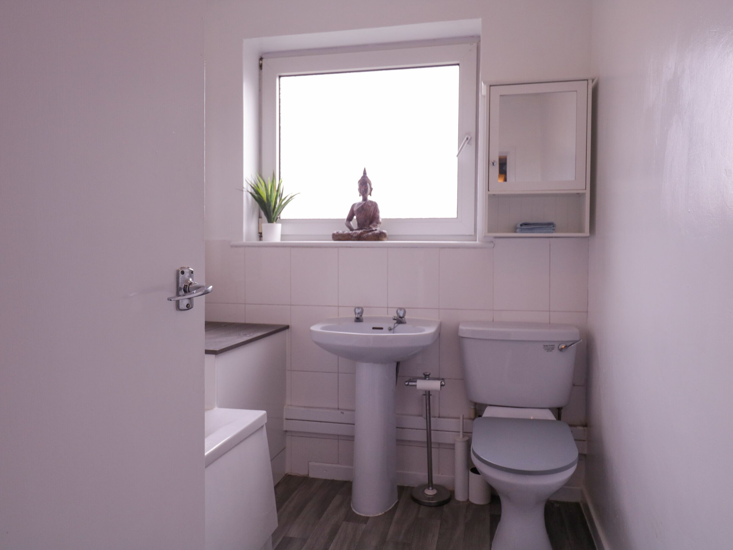 A small, modern bathroom with a toilet, sink, and window.