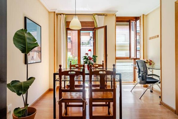 A dining area with a wooden table and chairs, a hanging light fixture, and a view of the outside.