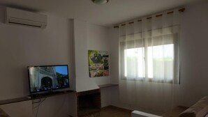 A living room with a television, a fireplace, and a large window with sheer curtains. - Villa California (Salou)