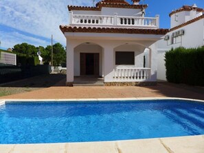 A two-story house with a swimming pool in front.