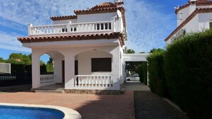 A white villa with a pool, a covered patio, and a view of a neighboring house. - Villa California (Salou)