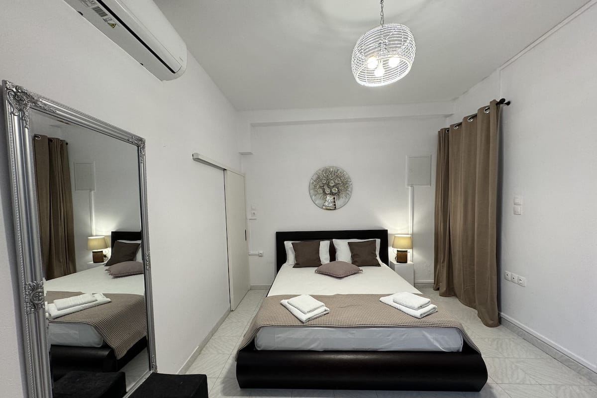 Une chambre d’hôtel avec un grand miroir, un lit doté d’une tête de lit noire, un élément de décoration circulaire au mur et un luminaire suspendu.