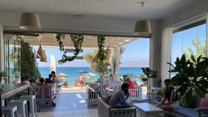 A terrace with outdoor seating, a view of the sea, and hanging plants. - Sunshine Bay Suites (Naxos)