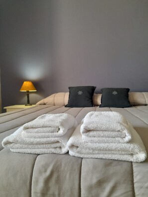 Cama com duas almofadas, abajur e duas toalhas dobradas.