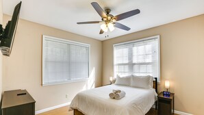 A bedroom with a bed, two bedside tables, a ceiling fan, and two windows with blinds. - Lake Seminole Retreat w/ Private Dock (Bainbridge)