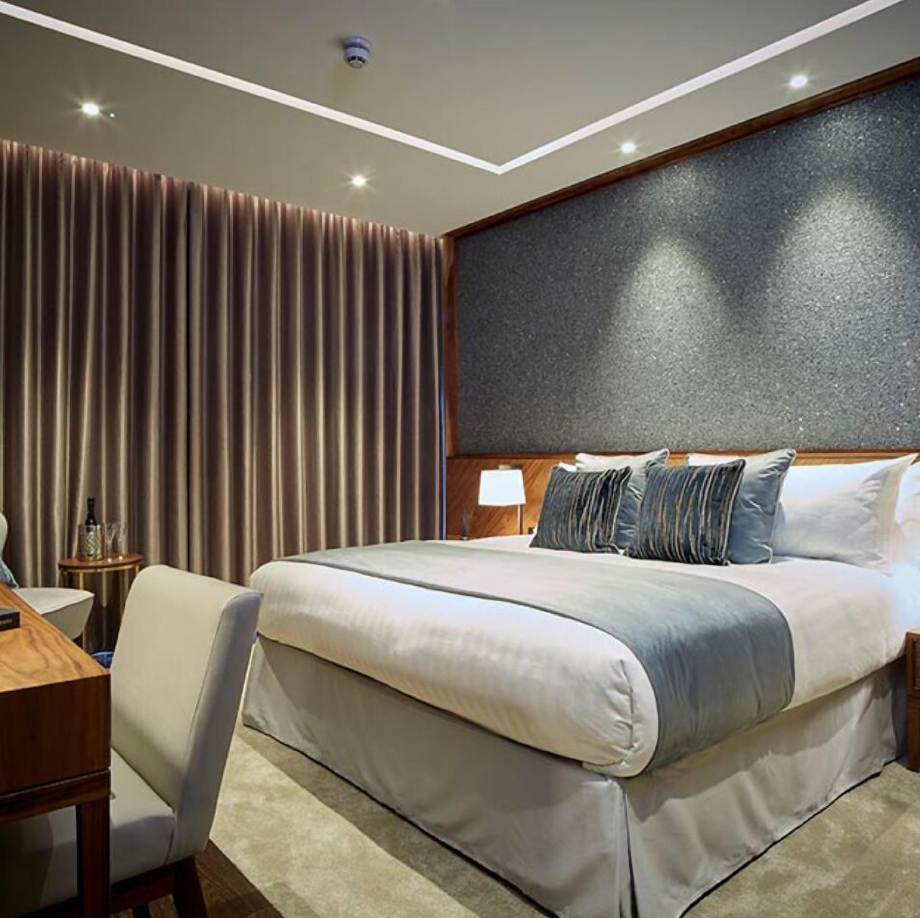 Una habitación de hotel moderna con una cama grande, un escritorio y una silla.