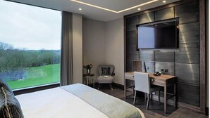 A modern hotel room with a large bed, a desk, and a TV mounted on the wall. - The Hotel at Mill Farm (Preston)