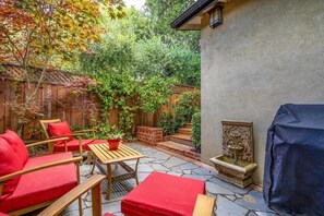 Een terras met rode meubels, een stenen vloer en een houten omheining.