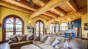 A spacious living room with a large sectional sofa, a dining area with a wooden table, and a kitchen with blue cabinets and stainless steel appliances. - Unique Cottage (Ghost Lake)