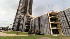 Un immeuble moderne de grande hauteur, doté de nombreux balcons et d’un toit plat.