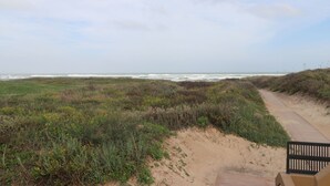 Un sentier côtier avec un banc, qui mène à la plage.