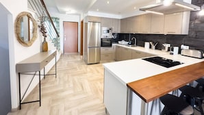 A modern kitchen with a central island, stainless steel appliances, and a wooden countertop.