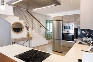 Een moderne keuken met een inbouwfornuis, roestvrijstalen apparatuur en een trap naar een ander niveau.