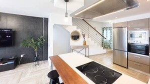 A modern kitchen with a central island, stainless steel appliances, and a staircase leading to an upper level.