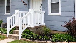 A two-story house with a front porch, a white door, and a mailbox. - Cozy 1 Bedroom Apartment (New Castle)