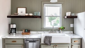 A kitchen with a built-in dishwasher, a coffee maker, and a window above the sink. - Cozy 1 Bedroom Apartment (New Castle)