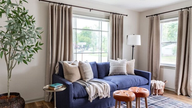 A living room with a blue sofa, a small round table, a floor lamp, a potted plant, and a patterned rug. - Cozy 1 Bedroom Apartment (New Castle)