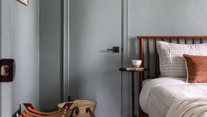 A bedroom with a bed, a wooden chair, a small table, and a door. - Cozy 1 Bedroom Apartment (New Castle)