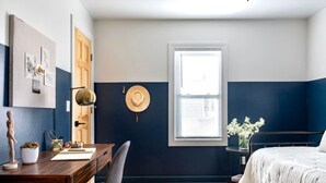 Une chambre à coucher avec un lit, un bureau, une chaise, une fenêtre et une porte.