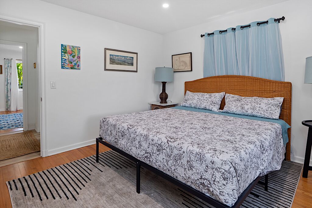 Une chambre à coucher avec un lit, une table de chevet, une lampe et une fenêtre avec des rideaux.