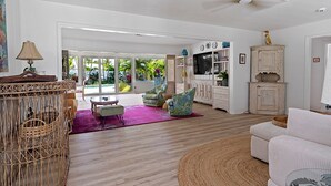A spacious living room with a large window, a ceiling fan, and a view of the outdoors.
