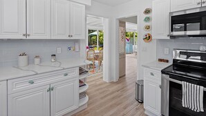 A modern kitchen with white cabinetry, a stainless steel stove, and a view to an outdoor patio.