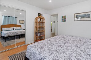 Un dormitorio con una cama grande, una estantería de madera y un ventanal corredero que da a otra habitación.