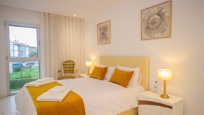 Habitación de hotel con una cama grande, dos lámparas de noche, una silla y una ventana con cortinas.