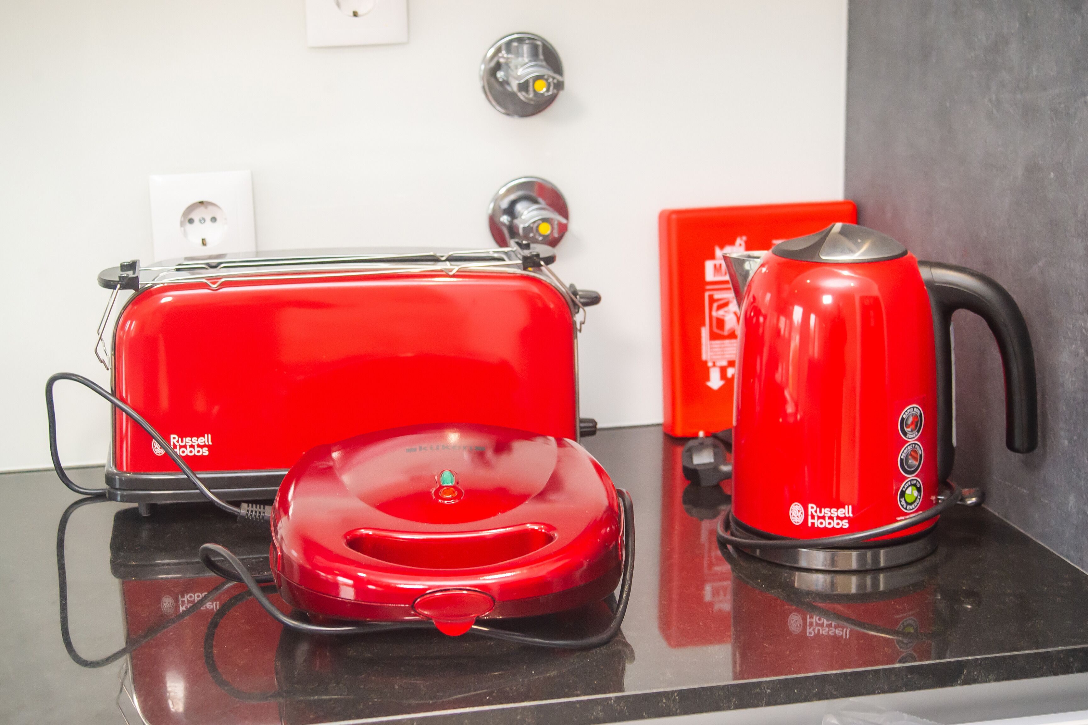 A red toaster and coffee maker on a kitchen counter.
