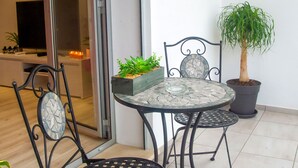 Un patio con una mesa y sillas, una planta en maceta y un televisor al fondo.