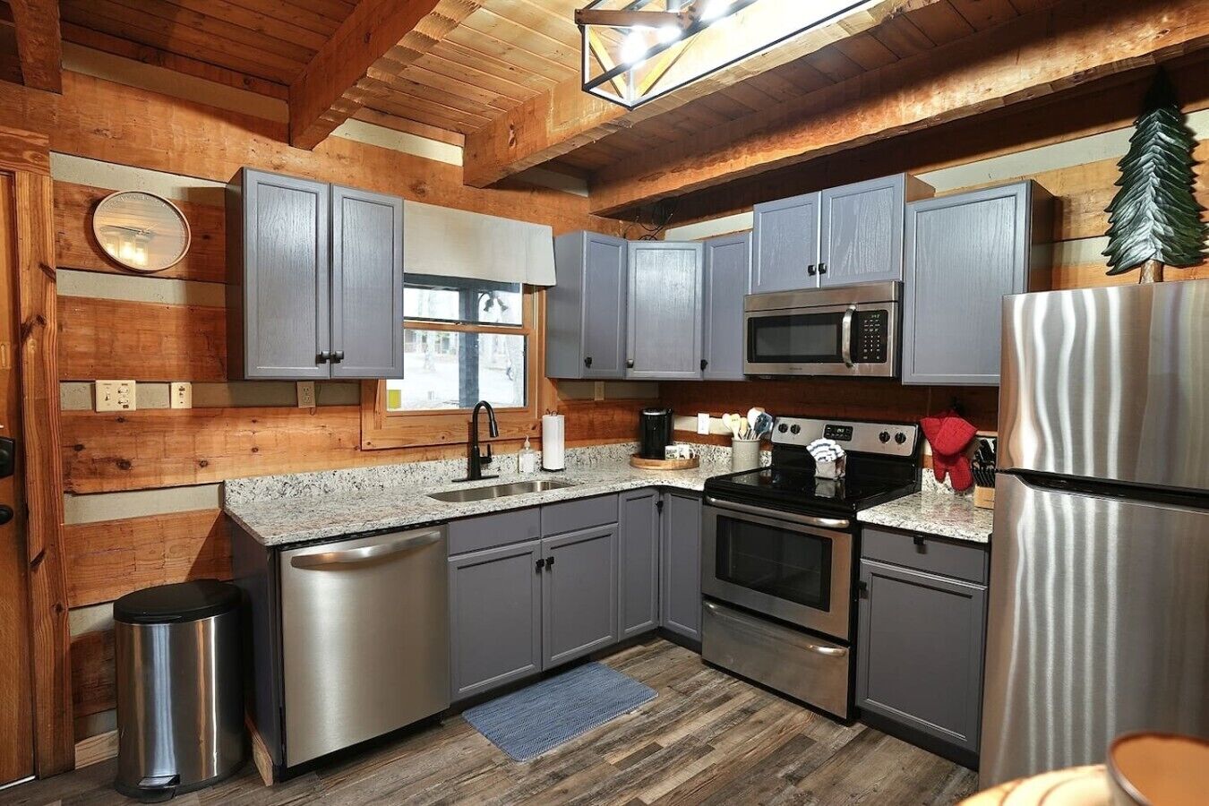 A compact kitchen with grey cabinets, a stainless steel refrigerator, a microwave, and an oven.