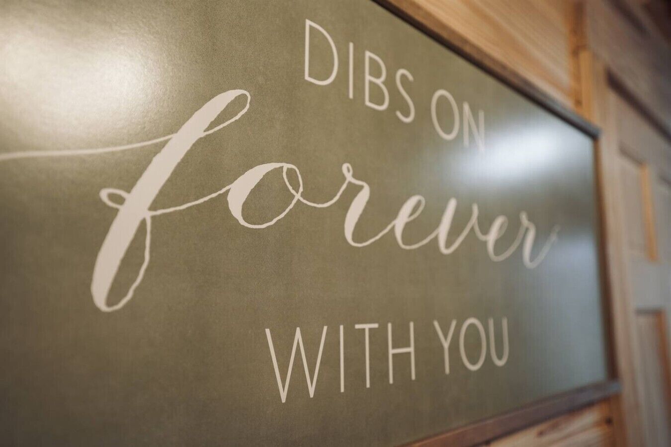 Un letrero con el texto 'DIBS ON forever with you' en una pared.