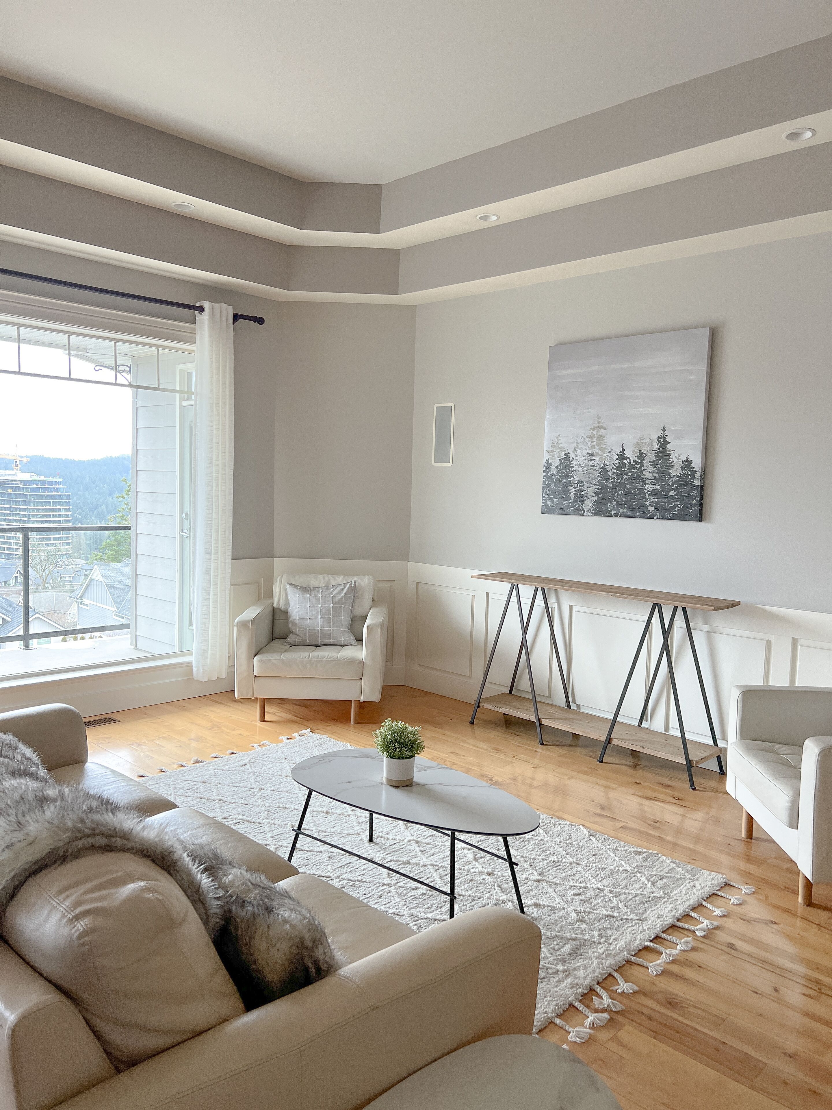 Ein modernes Wohnzimmer mit einer Couch, Sesseln, einem Couchtisch und einem Gemälde an der Wand.
