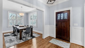 A dining area with a wooden table, chairs, and a chandelier. - Luxury 4BR in Historic District, Walk to Downtown (Greenville)
