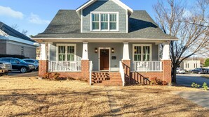 A two-story house with a front porch, a garage, and a driveway. - Luxury 4BR in Historic District, Walk to Downtown (Greenville)