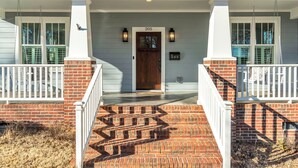 A two-story house with a front porch, a brick entrance, and a number 205 sign above the door. - Luxury 4BR in Historic District, Walk to Downtown (Greenville)
