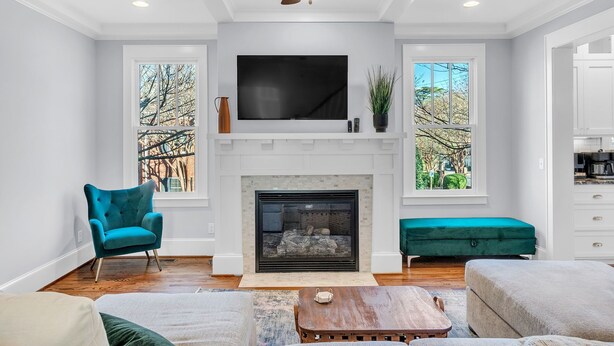 A modern living room with a fireplace, a large TV, and comfortable seating. - Luxury 4BR in Historic District, Walk to Downtown (Greenville)