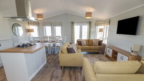 A modern living room with a sofa, a coffee table, and a TV mounted on the wall. - 4 Meadow Retreat (Liskeard)
