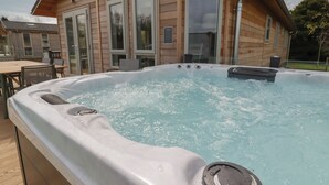A hot tub with a wooden deck and a house in the background. - 4 Meadow Retreat (Liskeard)