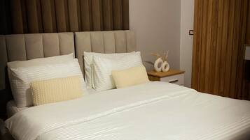 A neatly made bed with white linens and a headboard with vertical slats.