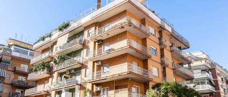 Un immeuble résidentiel à plusieurs étages, doté de balcons et de climatiseurs, avec un ciel dégagé.