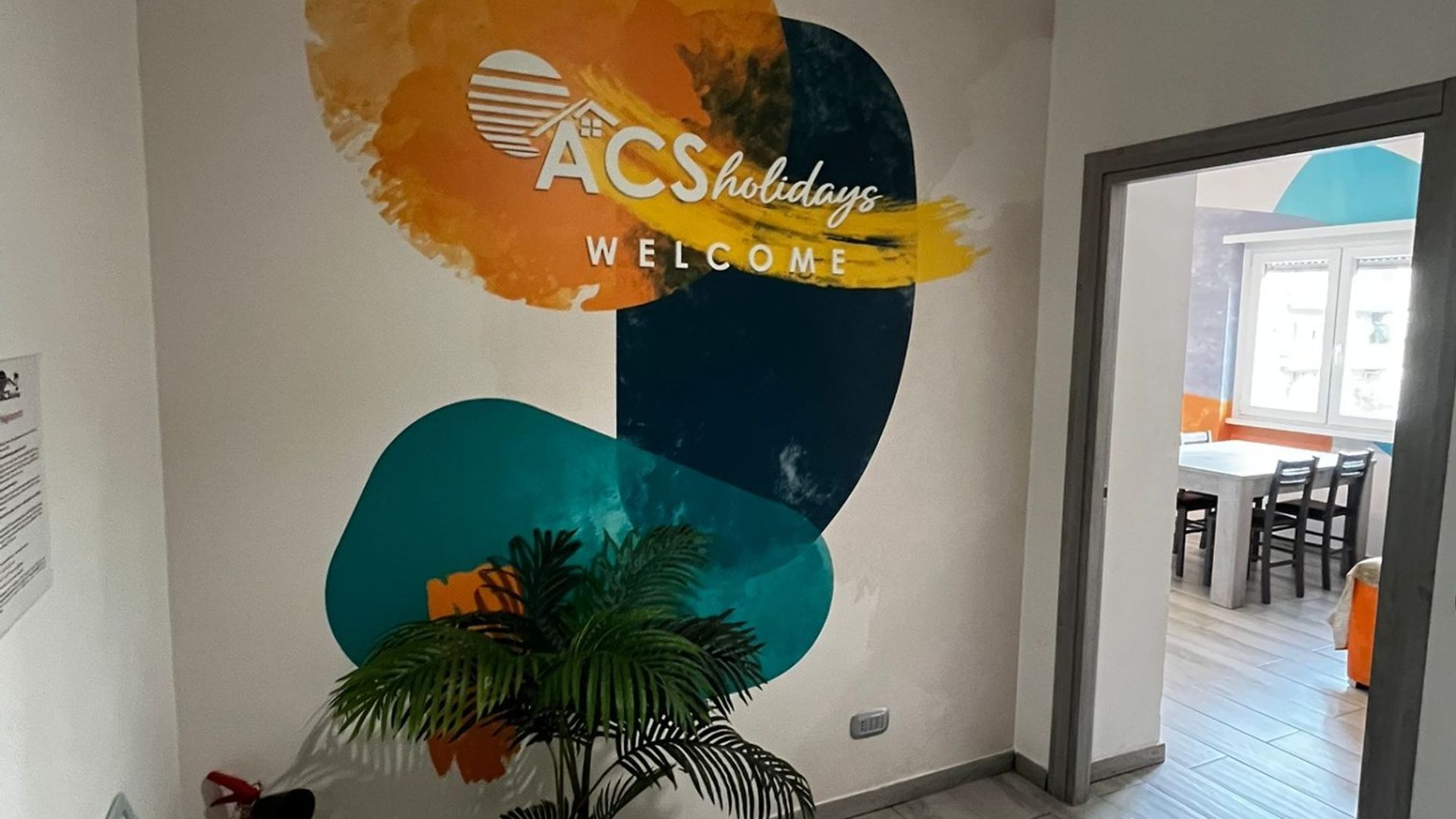 Eine Wand mit einem Logo und der Aufschrift 'ACSHolidays Welcome'.
