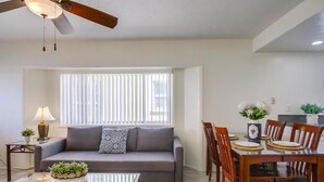 Un salon moderne comprenant un canapé, une table à manger, des chaises et un ventilateur de plafond.