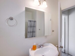 Une salle de bain avec un lavabo blanc, un miroir et un porte-serviettes.