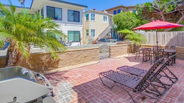 Un espace patio avec une piscine, des chaises longues et un parasol rouge.