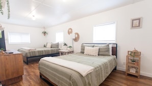 Un dormitorio con dos camas individuales, un aparador de madera y una mesita con una planta.