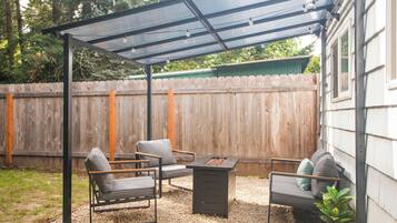 Un patio couvert comprenant un barbecue, deux chaises et une table.